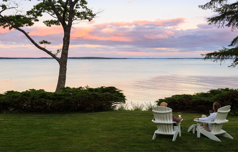 Couple in Adirondack chairs relaxing with wine